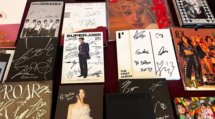 Various media signed by K-Pop stars displayed on a table.