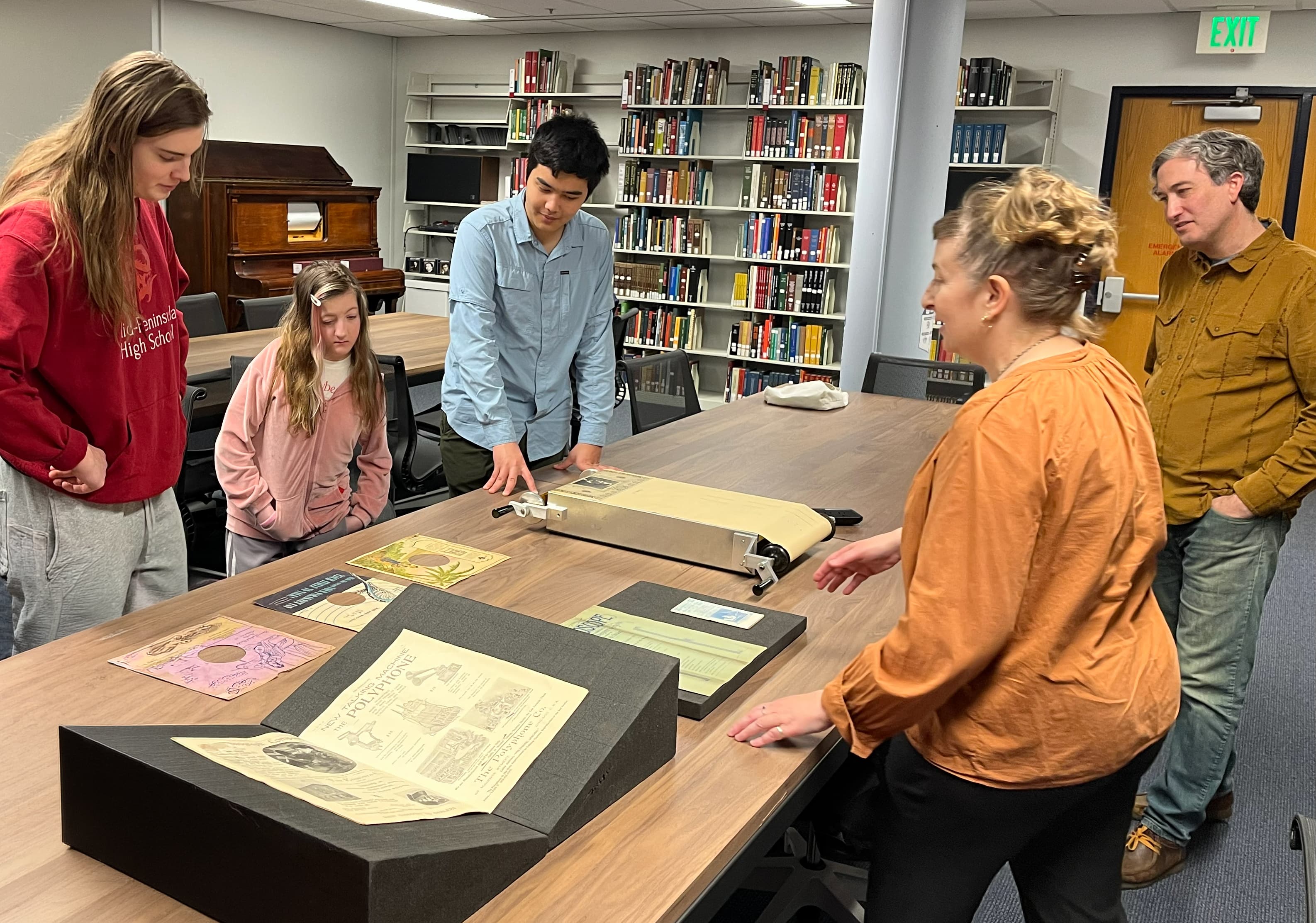 Students and staff gathered around rare materials displayed on a table.