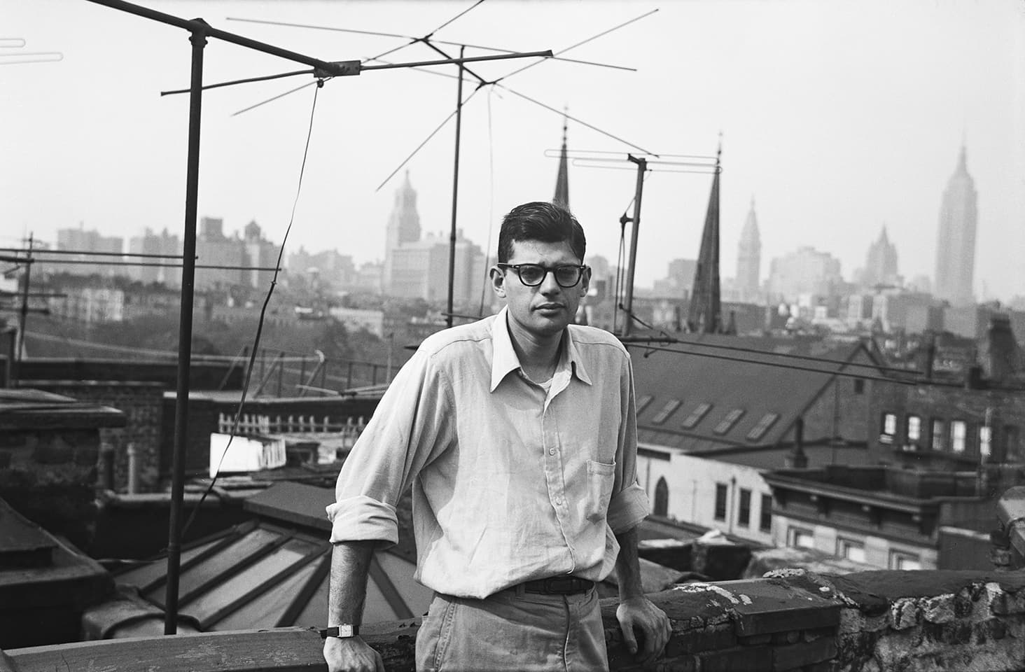 A man dressed in a smart-casual style standing on a roof in New York City