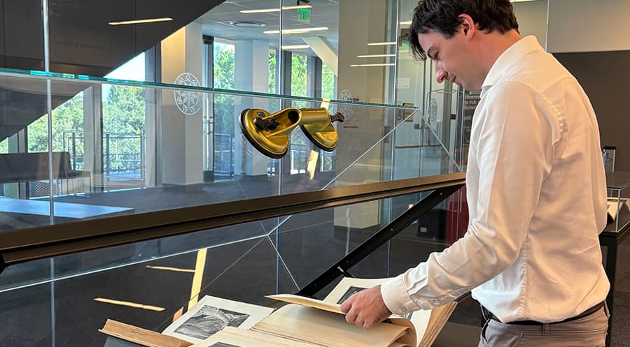 A man looking at and arranging items in an open exhibit case.