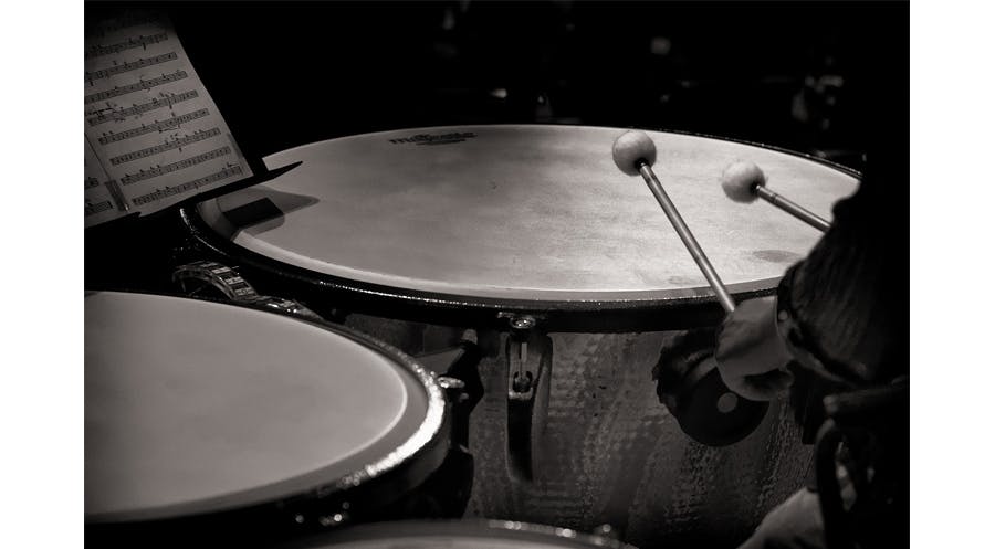 Close up of a symphonic timpani drummer's hand and mallets while performing.