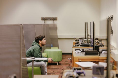 A person sitting down on a couch, playing video games.
