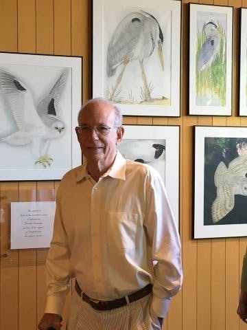 Stanford President Emeritus Donald Kennedy standing next to the bird gallery wall in Green Library
