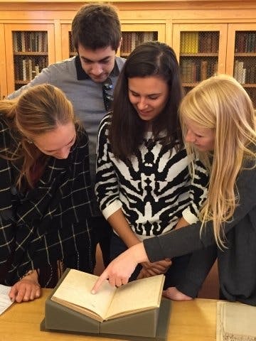 Students in Special Collections looking at the open page of a book.