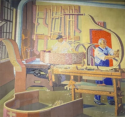 Mural of a piano factory with two people at work tables carving and working on large wooden pieces of a piano.