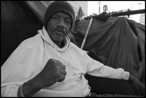 General TC, who calls himself The Peoples’ General, and lives on the sidewalk in Skid Row, faces the camera with one hand in a fist. 2014. The David Bacon Archive, Department of Special Collections, Stanford Libraries