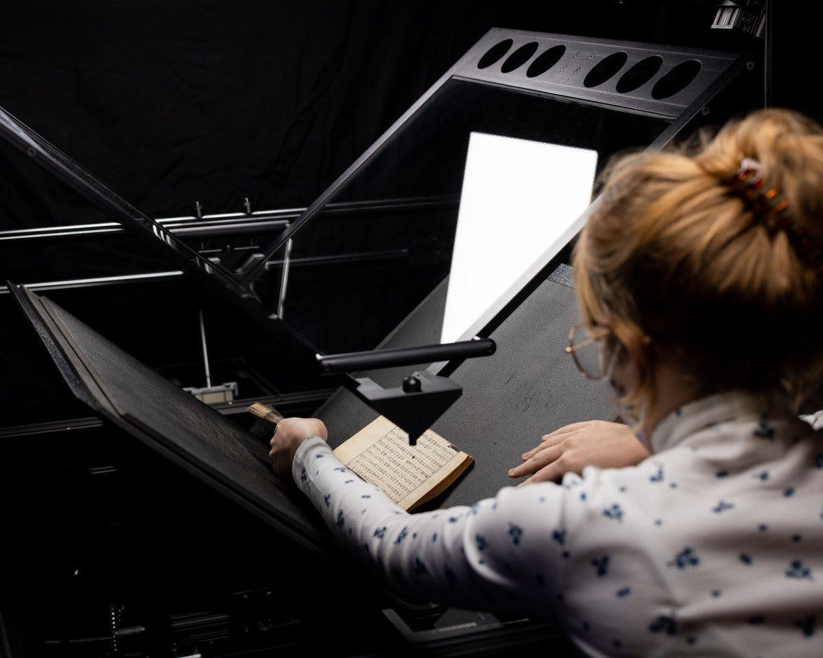 Library staff scanning a Chinese rare book using a high-end book scanner.